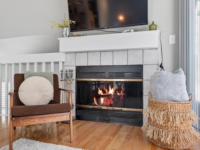 living area featuring a tiled fireplace and hardwood / wood-style flooring