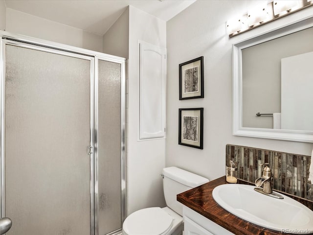 bathroom with toilet, vanity, and a shower with door