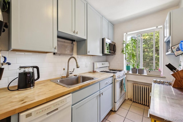 85 N Grant St Unit 28, Denver, CO 80203 - kitchen with radiator heating unit, white appliances, a sink, decorative backsplash, and light tile patterned flooring