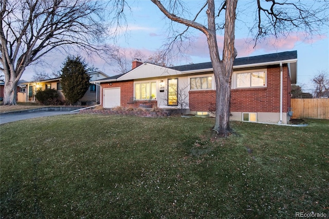 ranch-style house featuring a chimney, aphalt driveway, fence, a yard, and brick siding