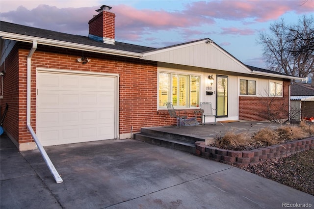 single story home with a garage, brick siding, driveway, and a chimney