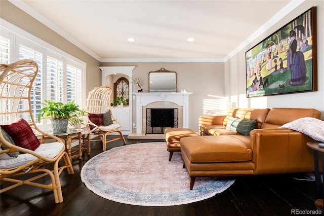 living area featuring ornamental molding, recessed lighting, dark wood-style flooring, and a fireplace with raised hearth