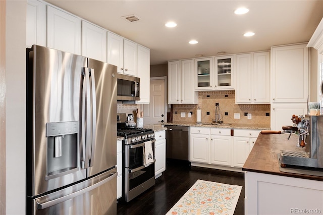 kitchen featuring stainless steel appliances, visible vents, decorative backsplash, white cabinets, and a sink