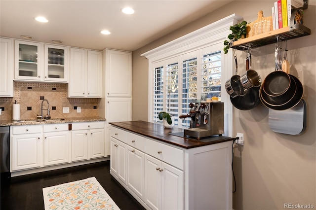 kitchen featuring tasteful backsplash, a sink, glass insert cabinets, and white cabinetry