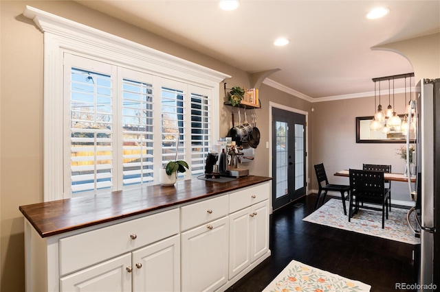 kitchen featuring dark wood finished floors, butcher block counters, ornamental molding, freestanding refrigerator, and french doors