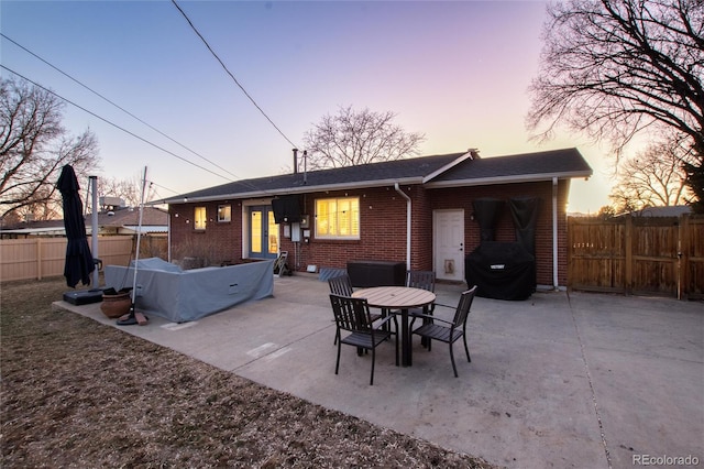 rear view of property featuring brick siding, a patio area, and fence