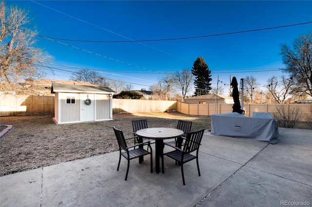 view of patio featuring an outbuilding, a shed, outdoor dining area, and a fenced backyard