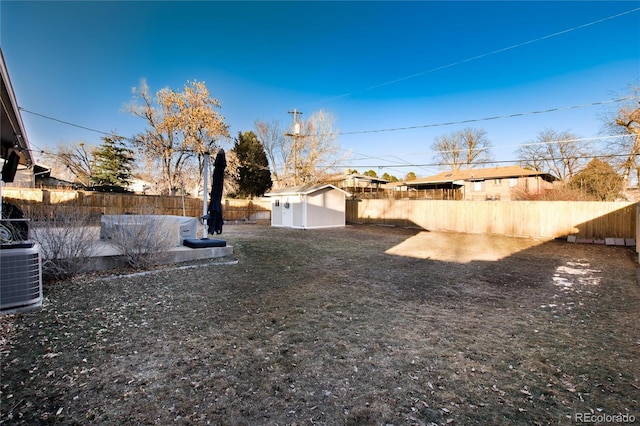 view of yard featuring a storage unit, a fenced backyard, an outdoor structure, and cooling unit