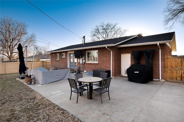 rear view of property featuring french doors, brick siding, a patio, and fence