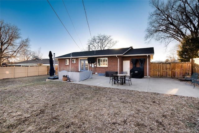 rear view of property with a patio area, a fenced backyard, french doors, and brick siding