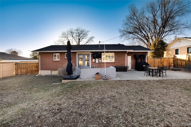 rear view of house with a patio, brick siding, and a fenced backyard