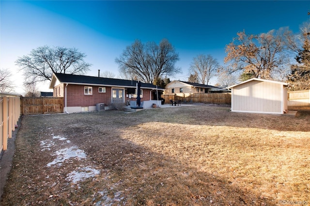 rear view of property with brick siding, a shed, cooling unit, a fenced backyard, and an outdoor structure