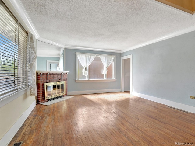 unfurnished living room with hardwood / wood-style floors, ornamental molding, a textured ceiling, and a fireplace