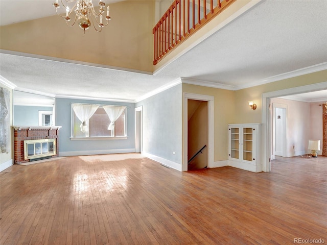 unfurnished living room featuring hardwood / wood-style flooring, crown molding, and a brick fireplace