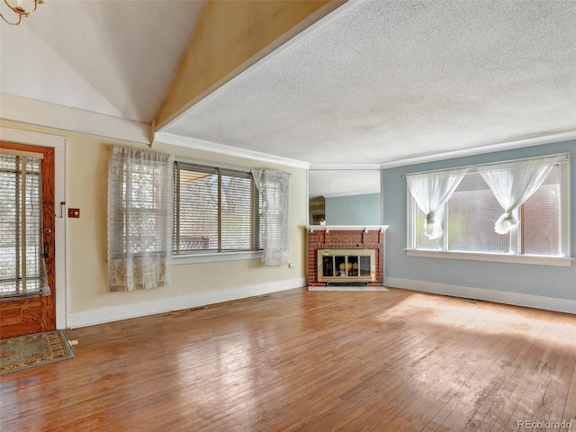 unfurnished living room with hardwood / wood-style flooring, a brick fireplace, lofted ceiling, and a textured ceiling