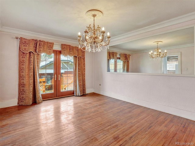 spare room with a notable chandelier, crown molding, wood-type flooring, and french doors