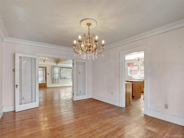 unfurnished dining area with hardwood / wood-style flooring, crown molding, a wealth of natural light, and a notable chandelier