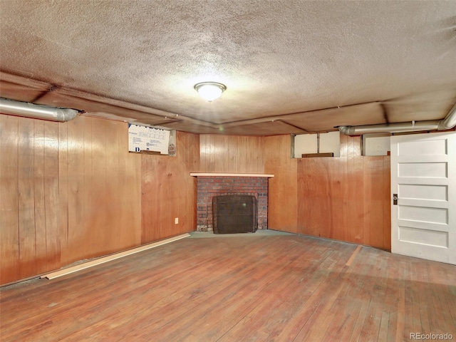 basement featuring wood-type flooring, a textured ceiling, a fireplace, and wood walls