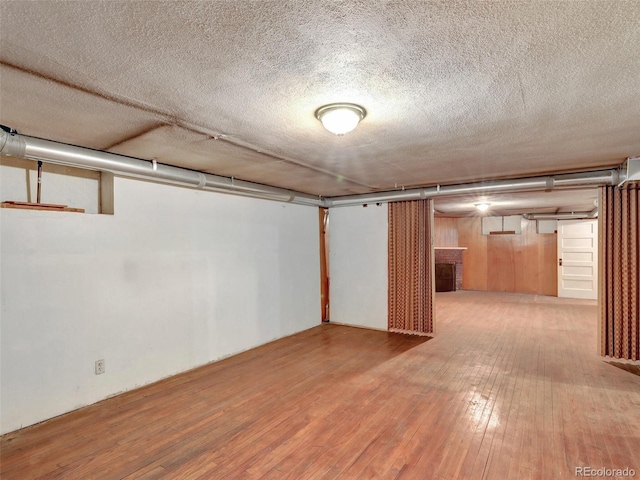 basement with hardwood / wood-style flooring and a textured ceiling