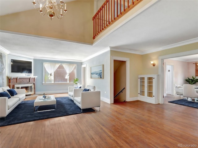 living room with ornamental molding, a towering ceiling, a notable chandelier, and light hardwood / wood-style floors