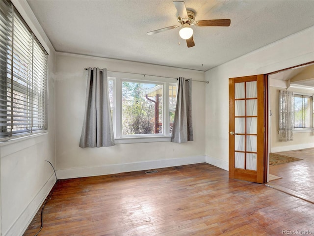 empty room featuring wood-type flooring, ceiling fan, and a textured ceiling