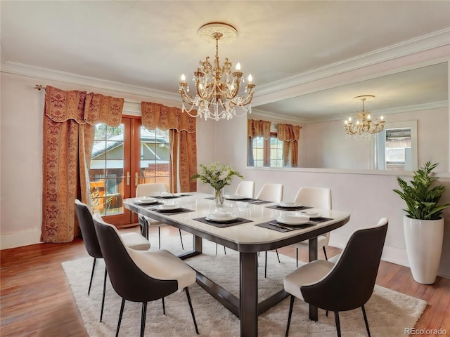 dining room with an inviting chandelier, ornamental molding, light hardwood / wood-style floors, and french doors