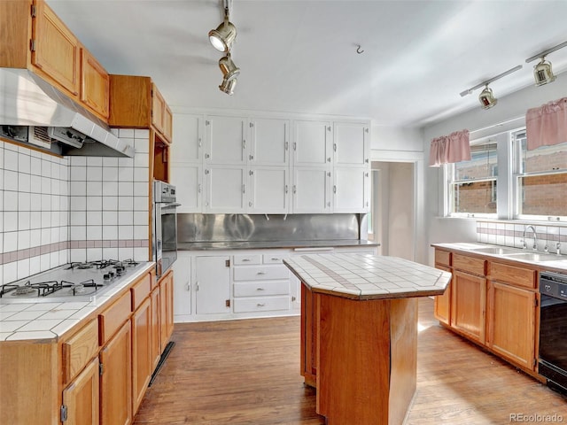 kitchen featuring a kitchen island, black dishwasher, tile counters, stainless steel oven, and gas cooktop