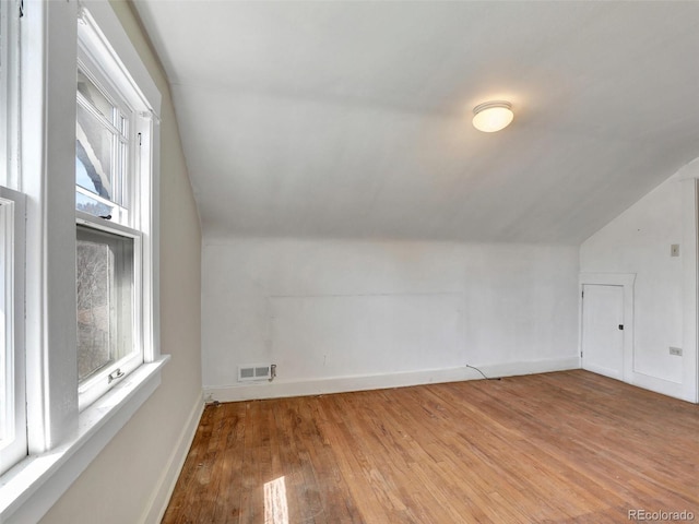 additional living space featuring lofted ceiling and light hardwood / wood-style flooring