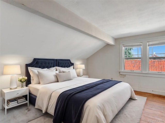 bedroom featuring lofted ceiling with beams and light wood-type flooring