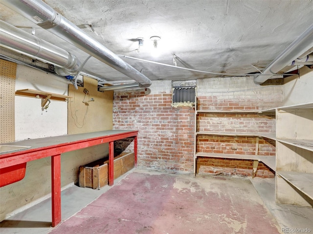 basement with a workshop area and brick wall