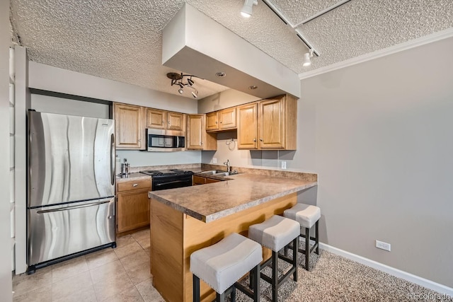 kitchen with appliances with stainless steel finishes, a textured ceiling, rail lighting, and sink