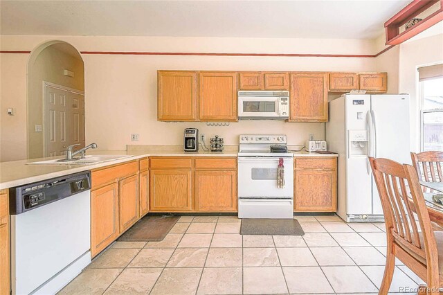 kitchen featuring light tile patterned flooring, white appliances, and sink