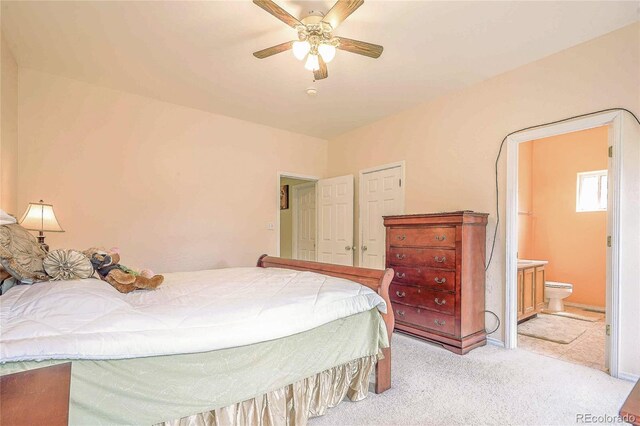 bedroom with ceiling fan, ensuite bath, and light carpet