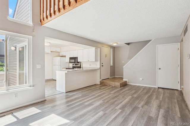 2453 S Xanadu Way Unit C, Aurora, CO 80014 - unfurnished living room featuring light wood-type flooring, stairway, and a textured ceiling