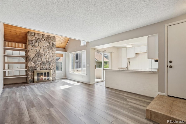 2453 S Xanadu Way Unit C, Aurora, CO 80014 - unfurnished living room with wood finished floors, a textured ceiling, a fireplace, and vaulted ceiling