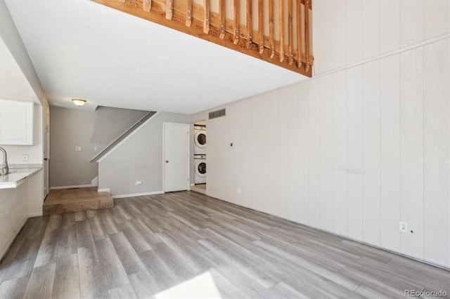 2453 S Xanadu Way Unit C, Aurora, CO 80014 - unfurnished living room with stacked washer / drying machine, light wood-style flooring, and stairs