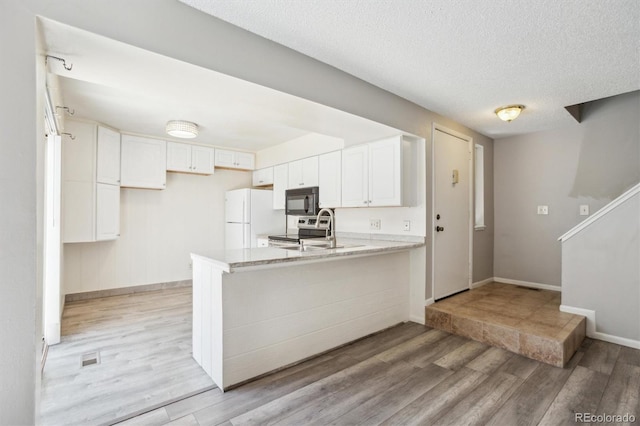 2453 S Xanadu Way Unit C, Aurora, CO 80014 - kitchen featuring black microwave, stainless steel electric range oven, freestanding refrigerator, a peninsula, and light wood finished floors