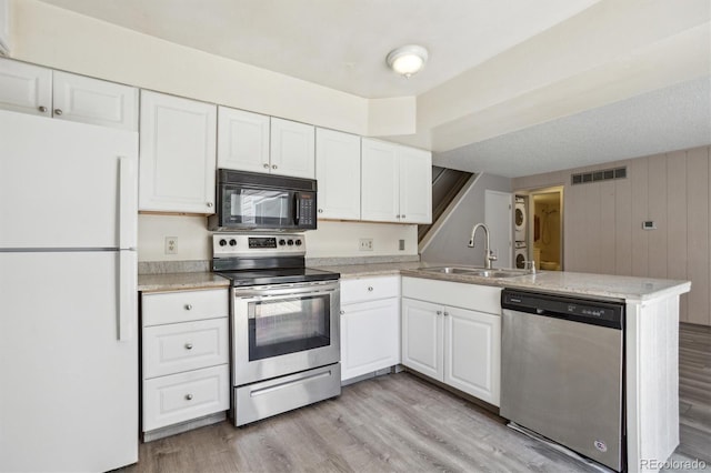 2453 S Xanadu Way Unit C, Aurora, CO 80014 - kitchen with appliances with stainless steel finishes, a peninsula, white cabinetry, and light wood-style floors