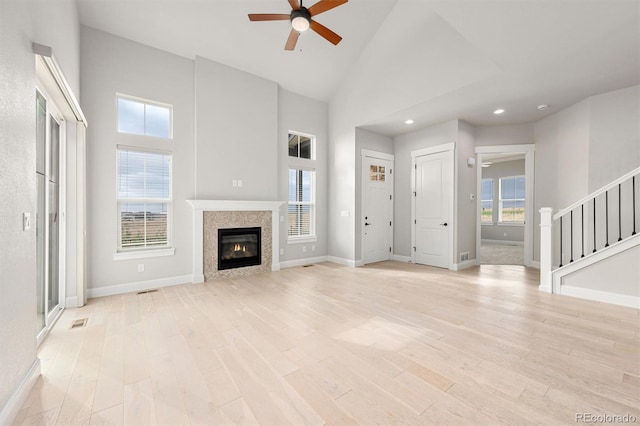 unfurnished living room with stairs, high vaulted ceiling, baseboards, and light wood-style floors