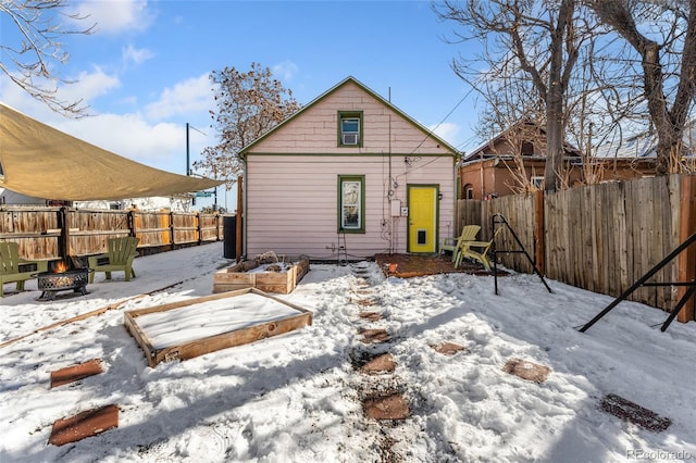 snow covered property featuring an outdoor fire pit and a fenced backyard