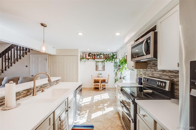 kitchen with a sink, light countertops, appliances with stainless steel finishes, tasteful backsplash, and decorative light fixtures