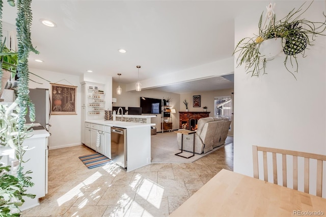 kitchen featuring light countertops, stainless steel dishwasher, a sink, a warm lit fireplace, and a peninsula