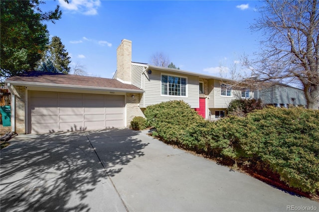 split foyer home with brick siding, a chimney, and an attached garage