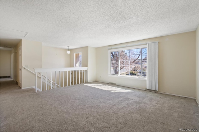 spare room featuring a textured ceiling, carpet floors, and baseboards