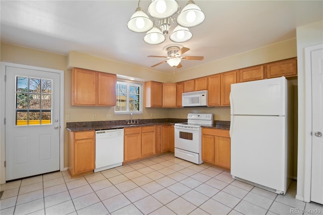 kitchen featuring dark countertops, white appliances, light tile patterned flooring, and ceiling fan with notable chandelier