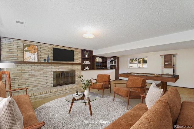 carpeted living area with a textured ceiling, brick wall, a fireplace, and visible vents