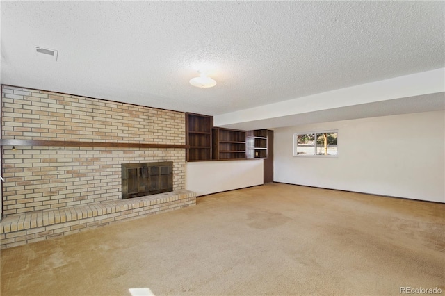 unfurnished living room with a textured ceiling, carpet floors, a brick fireplace, and visible vents