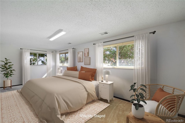 bedroom featuring baseboards, multiple windows, visible vents, and a textured ceiling