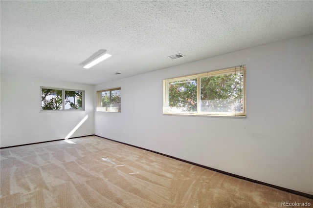 spare room featuring baseboards, a textured ceiling, visible vents, and carpet flooring