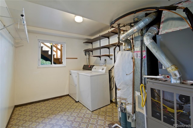 laundry area with laundry area, light floors, washing machine and clothes dryer, and baseboards